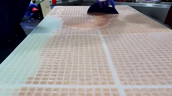 Large reusable commercial silicone gummy molds filled during a real starchless gummy production run